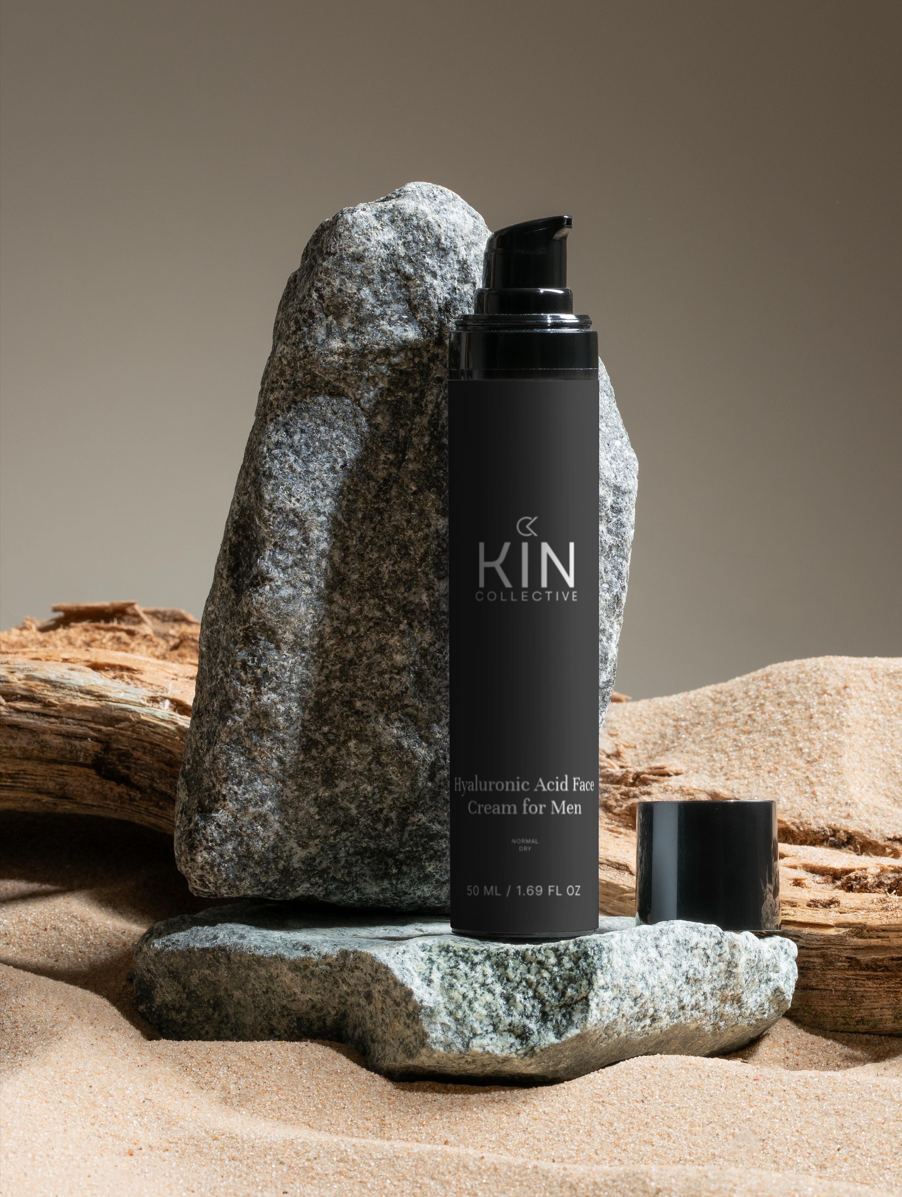 Men's hyaluronic acid face cream bottle on natural rocks and sand, skincare product
